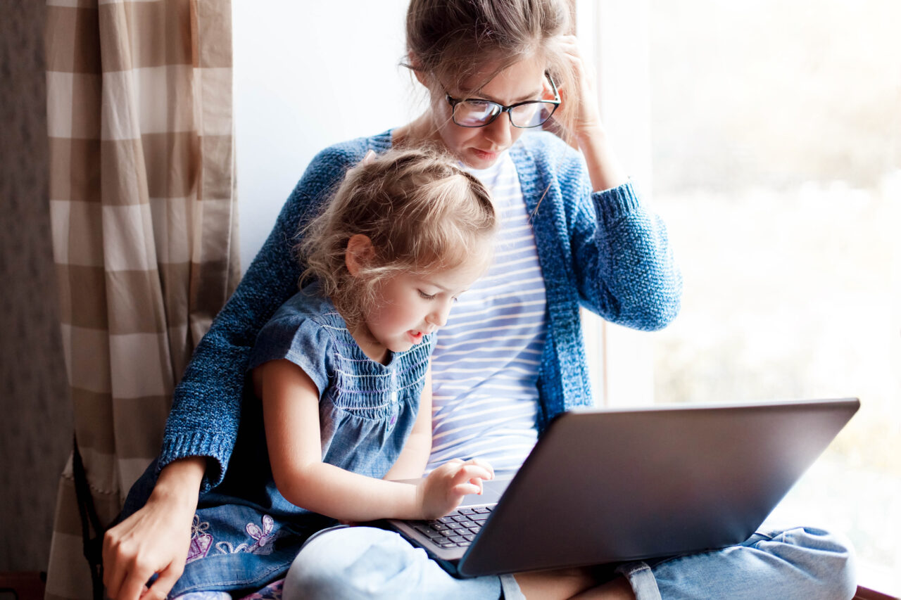 Bildnachweis: Marina Andrejchenko / Shutterstock Mutter und Tochter am Laptop auf der Fensterbank sitzend